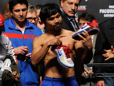 LAS VEGAS, NV - NOVEMBER 11: Boxer Manny Pacquiao appears on stage and points to his NIKE shoes during the official weigh-in for his bout against Juan Manuel Marquez at the MGM Grand Garden Arena November 11, 2011 in Las Vegas, Nevada. Pacquiao will defend his WBO welterweight title against Marquez when the two meet in the ring for the third time on November 12 in Las Vegas. (Photo by Ethan Miller/Getty Images)