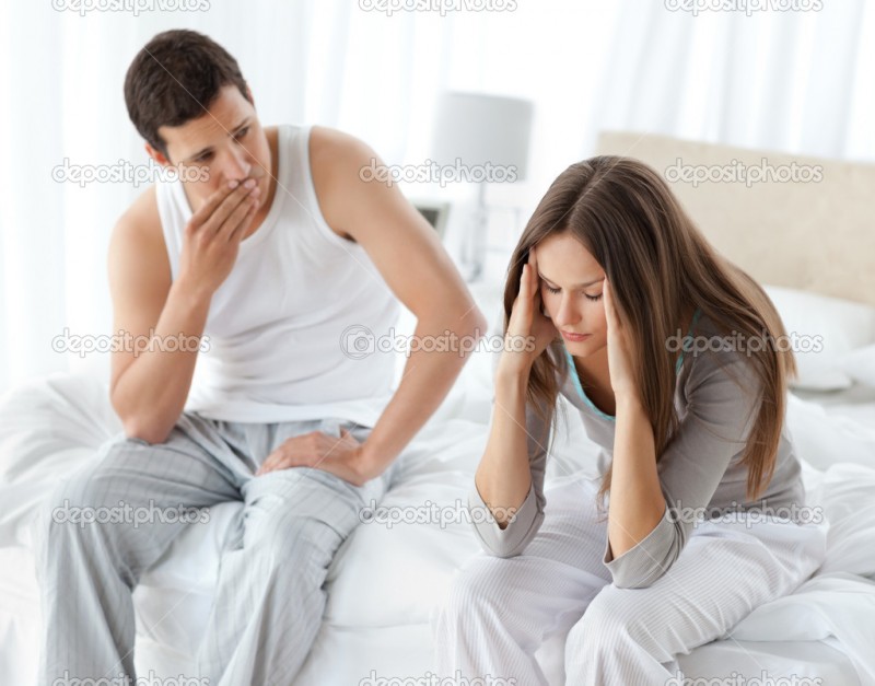 Worried man looking at his girlfriend having a headache on the b